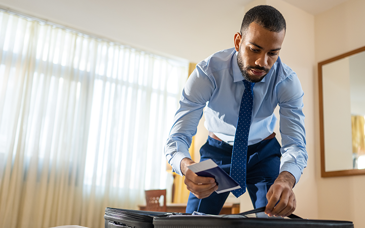 Man packing a suitcase with neatly folded clothes, representing a business travel checklist