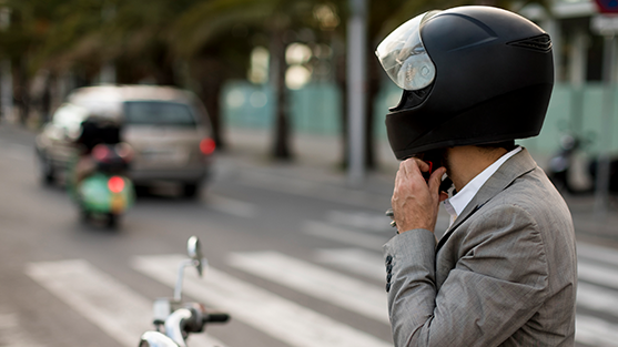 A man sits confidently on a sleek motorbike, fastening his helmet enjoying  convenience and adventure of the Hertz car rental loyalty programme